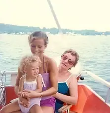 A family photograph: three generations together on a boat on open water.